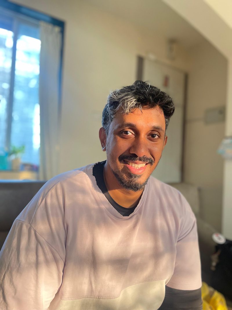 Nilesh smiling in a sunlit room at home