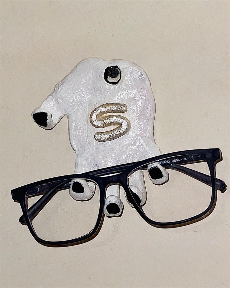 Handmade white hand-shaped wall hook holding a pair of glasses